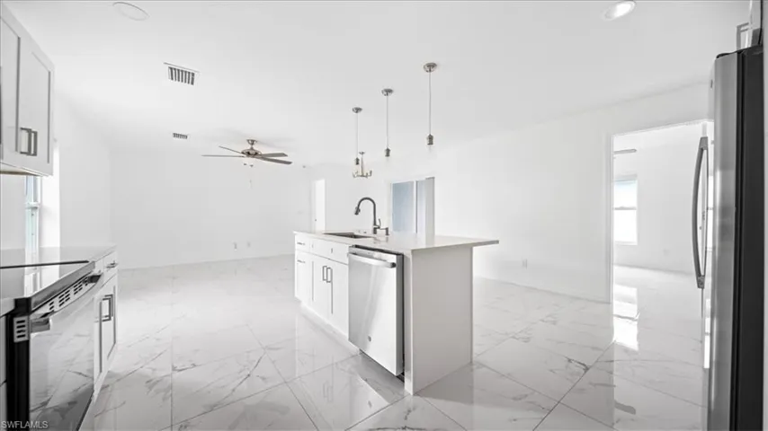 Kitchen with light marble finish floors, appliances with stainless steel finishes, hanging light fixtures, white cabinetry, and recessed lighting