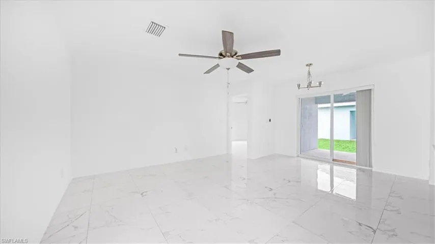 Unfurnished room with light marble finish floors, a chandelier, and a ceiling fan