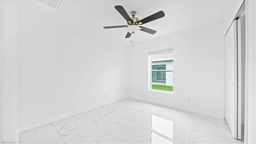 Unfurnished bedroom featuring light marble finish flooring, a ceiling fan, and a closet
