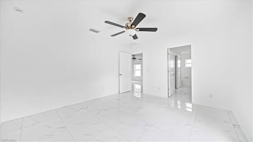 Unfurnished bedroom with light marble finish floors, ceiling fan, and ensuite bath