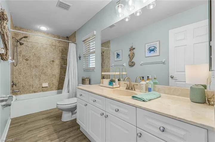 Full guest bath #1 featuring vanity, shower / tub combo, and light wood-type flooring