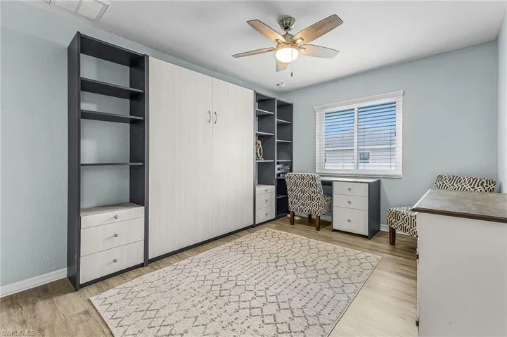 Guest bedroom #1 with Murphy bed and desk, a ceiling fan, and a textured wall