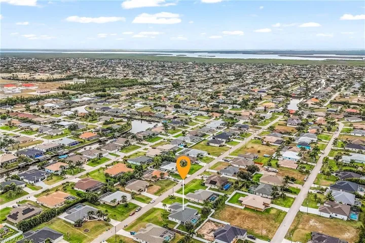 Aerial view of property and surrounding area featuring a nearby body of water and nearby suburban area