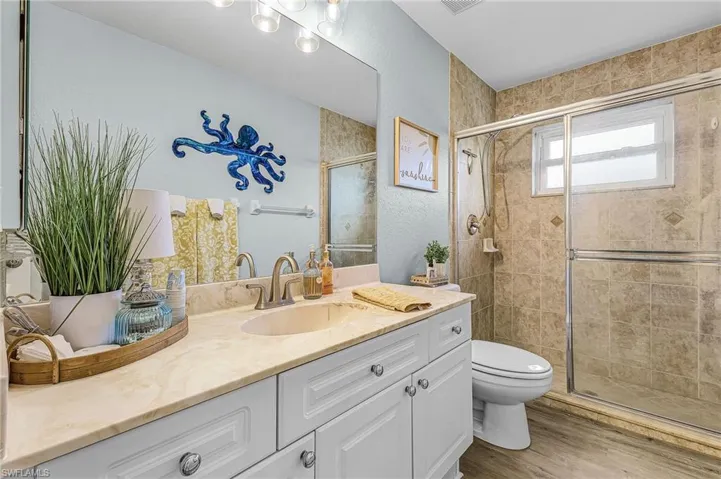 Bathroom with vanity, a shower stall, light wood-style flooring, and a textured wall