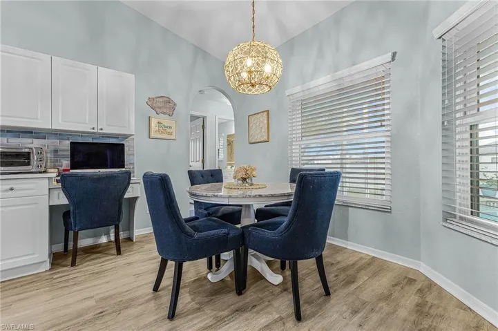 Dining room featuring arched walkways, light wood finished floors, and plenty of natural light