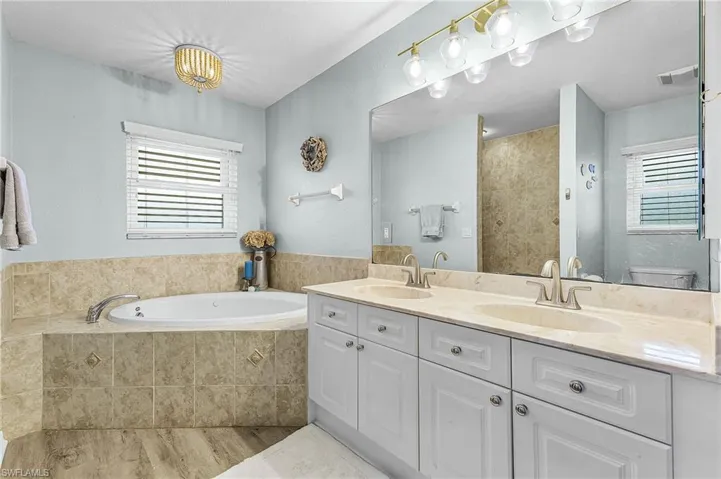 Primary bathroom featuring double vanity, garden tub, shower