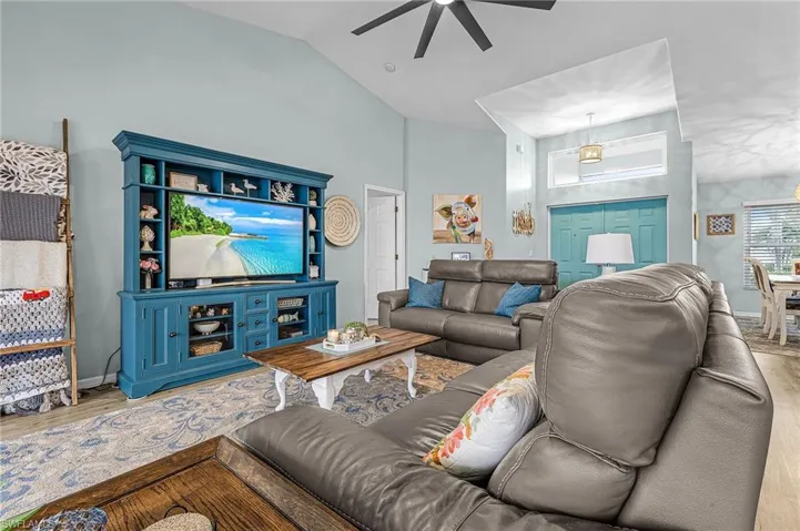 Living area with wood finished floors, ceiling fan, and high vaulted ceiling