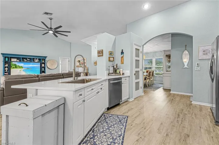 Kitchen with open floor plan, a peninsula, pantry, arched walkways, white cabinets, and ceiling fan