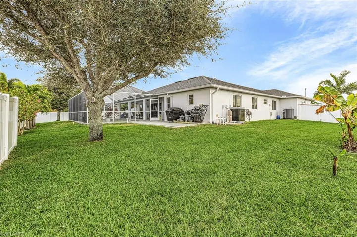 Back of house featuring a fenced backyard, stucco siding, a lanai, and a sunroom