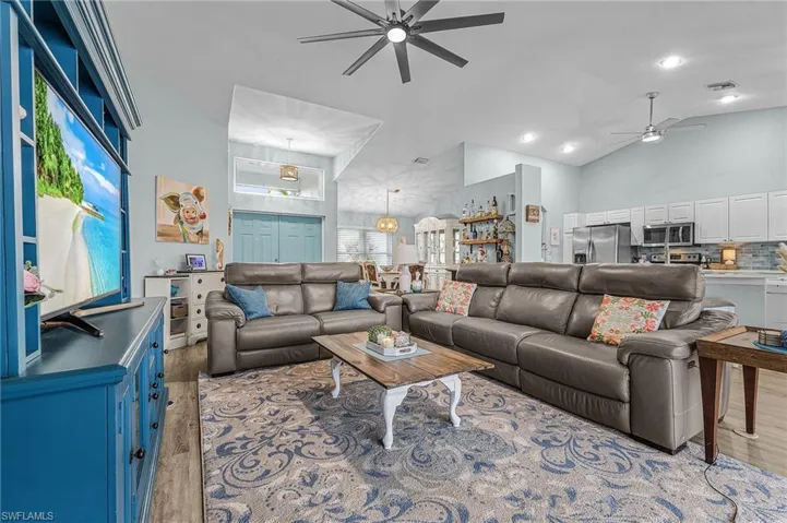 Living room featuring a ceiling fan, wood finished floors, and high vaulted ceiling