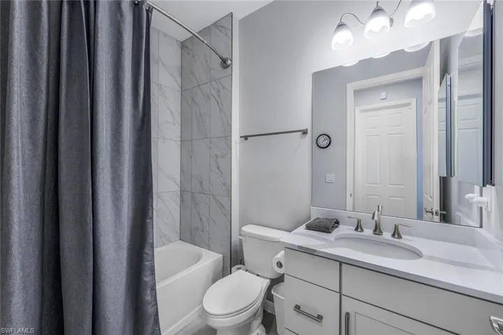 Full bathroom with shower / tub combo with curtain, oversized vanity, and toilet