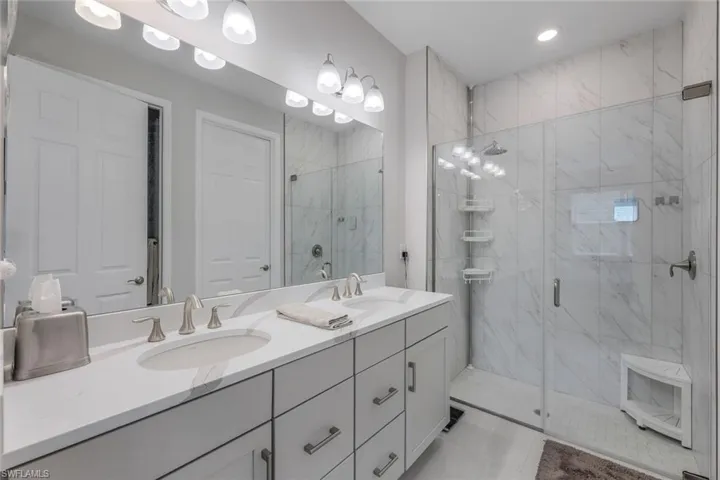Bathroom with tile flooring, an enclosed shower, and double sink vanity