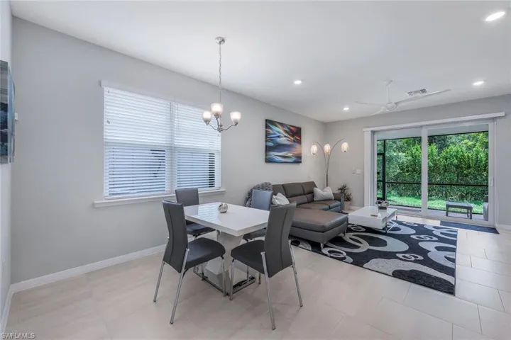 Dining room with light tile floors and ceiling fan with notable chandelier