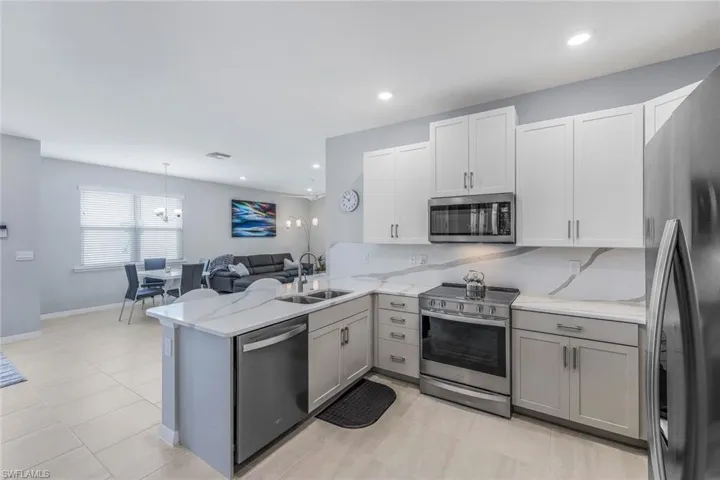 Kitchen featuring stainless steel appliances, kitchen peninsula, decorative light fixtures, sink, and light tile floors