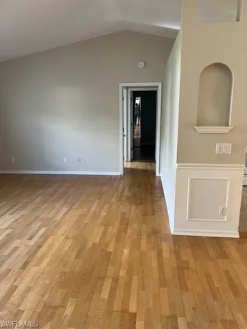 Spare room with light wood-type flooring and lofted ceiling