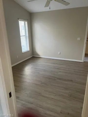 Spare room with ceiling fan, wood-type flooring, and lofted ceiling