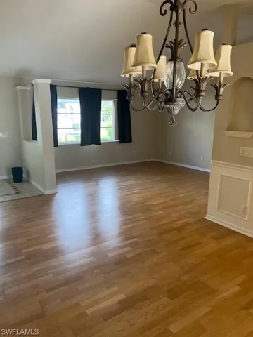 Unfurnished dining area with a notable chandelier and hardwood / wood-style floors