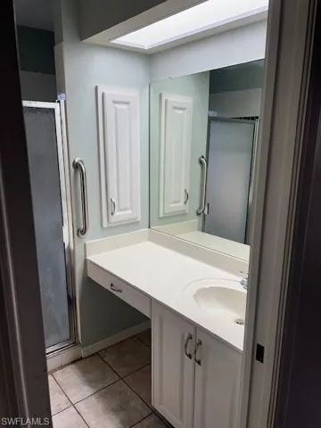 Bathroom with tile patterned floors, an enclosed shower, and vanity