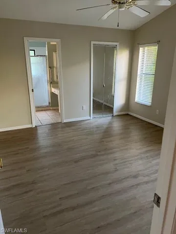 Empty room featuring ceiling fan, vaulted ceiling, and wood-type flooring