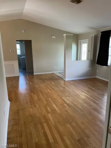 Empty room with vaulted ceiling and wood-type flooring