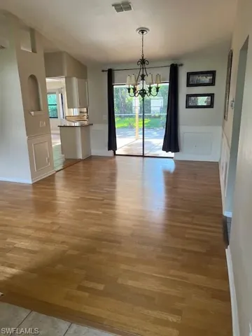 Unfurnished dining area featuring a wealth of natural light, a notable chandelier, and light hardwood / wood-style flooring