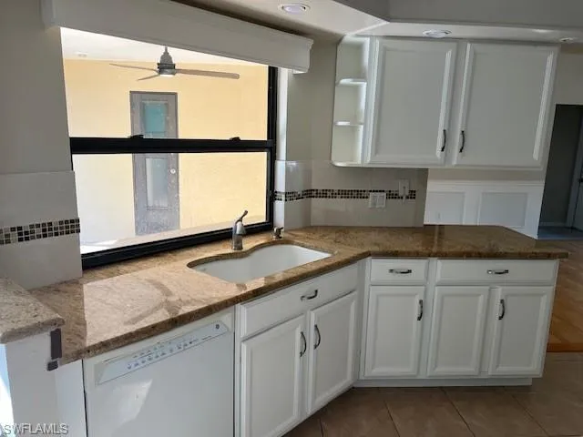 Kitchen with ceiling fan, decorative backsplash, stone countertops, dishwasher, and sink