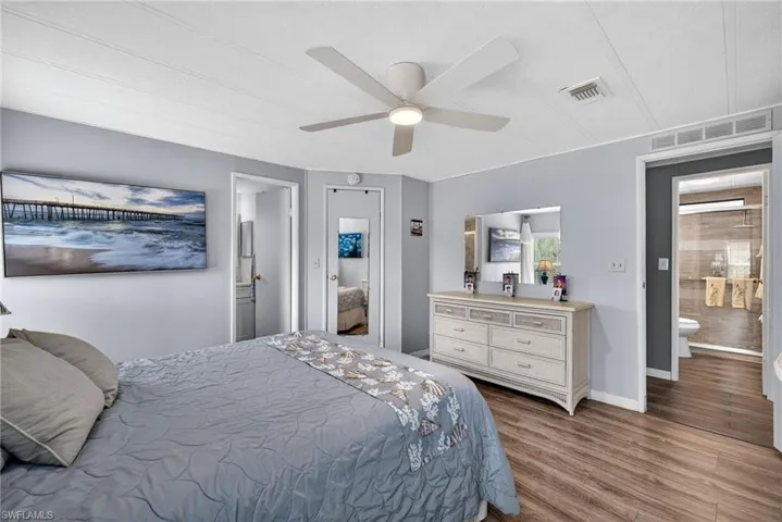 Bedroom featuring connected bathroom, dark wood-style floors, and ceiling fan