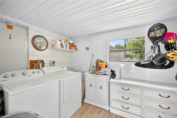 Laundry room with light wood finished floors, cabinet space, and washing machine and clothes dryer