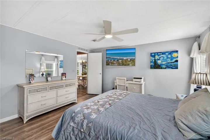 Bedroom featuring dark wood-style floors, ceiling fan, and multiple windows