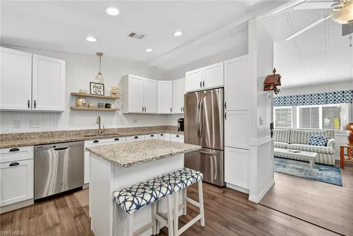 Kitchen featuring white cabinets, pendant lighting, stainless steel appliances, open shelves, and recessed lighting