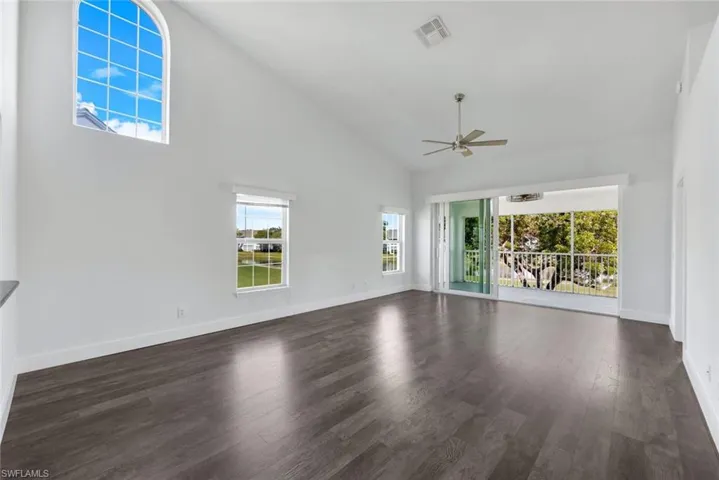 Unfurnished living room featuring high vaulted ceiling, dark hardwood / wood-style floors, and ceiling fan