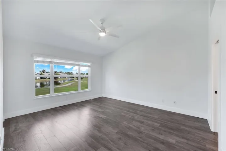 Spare room featuring ceiling fan, dark hardwood / wood-style floors, and vaulted ceiling