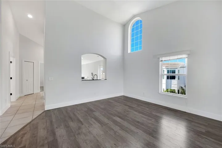 Unfurnished living room featuring wood-type flooring and high vaulted ceiling