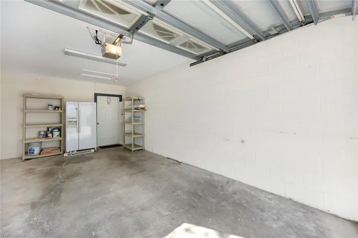 Garage featuring a garage door opener and white fridge with ice dispenser