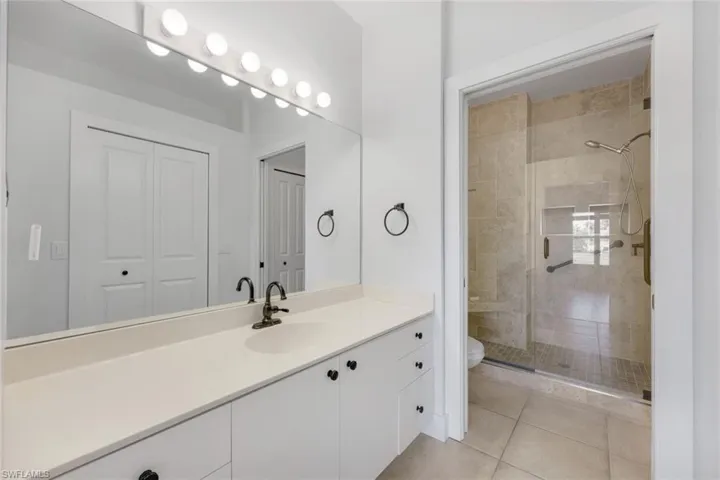 Bathroom featuring vanity, toilet, tile patterned flooring, and a shower with door