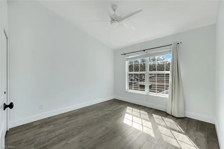 Unfurnished room with ceiling fan, lofted ceiling, and dark hardwood / wood-style floors