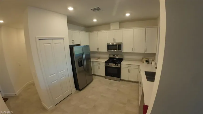 Kitchen featuring white cabinetry, stainless steel appliances, and recessed lighting