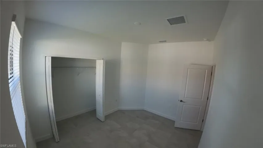 Unfurnished bedroom featuring light floors and a closet