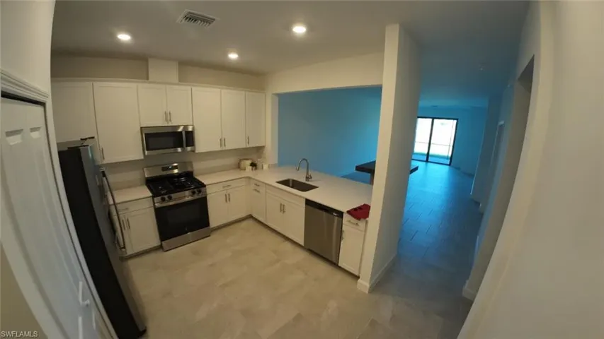 Kitchen with appliances with stainless steel finishes, white cabinets, and recessed lighting