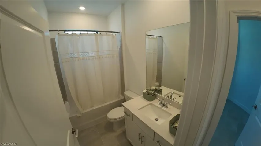 Bathroom featuring vanity, shower / bathtub combination with curtain, and tile patterned flooring