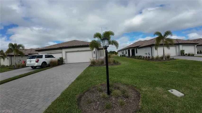 View of side of home with a yard, decorative driveway, stucco siding, and an attached garage