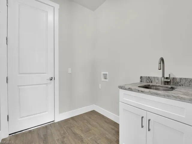 Laundry room featuring dark wood-style floors, washer hookup, and cabinet space