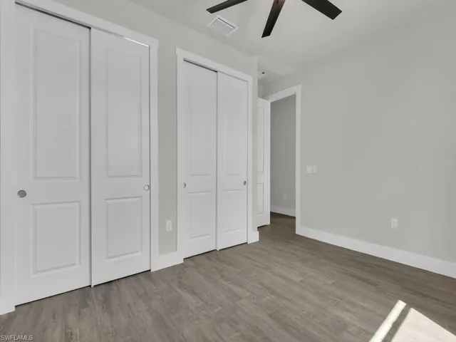 Unfurnished bedroom with two closets, light wood-type flooring, and a ceiling fan