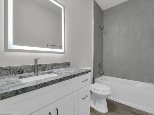 Full bath with vanity, shower / bathtub combination, and dark wood finished floors