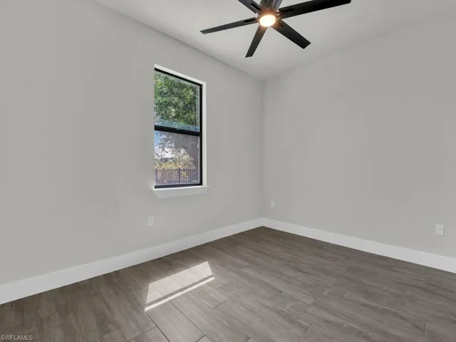 Unfurnished room featuring dark wood finished floors and ceiling fan
