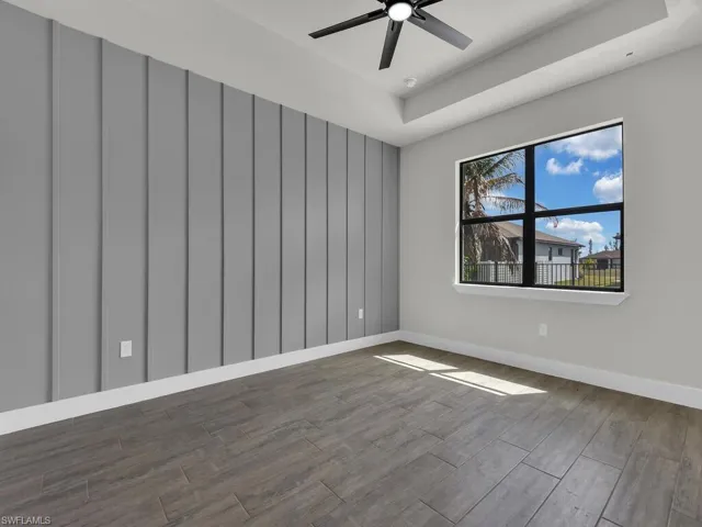 Spare room with dark wood-style floors, a raised ceiling, and ceiling fan