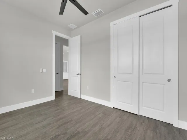 Unfurnished bedroom featuring dark wood-type flooring, a ceiling fan, and a closet