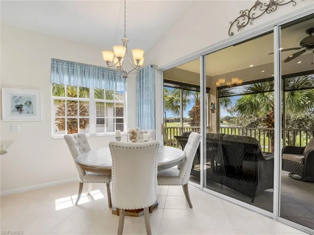 Breakfast area with a wealth of natural light, vaulted ceiling,  with notable chandelier, and light tile patterned floors