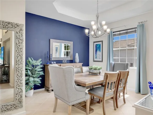 Dining room featuring light tile patterned flooring, a notable chandelier, and a raised ceiling
