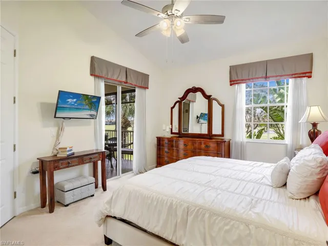 Primary Bedroom with vaulted ceiling, multiple windows, access to balcony and ceiling fan.